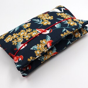May include: A dark blue fabric pouch with a red trim. The pouch is decorated with a floral pattern featuring yellow flowers and red birds.