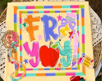 May include: A light yellow t-shirt featuring a colourful graphic with the text FRY YAY, a red apple, a yellow pencil with a purple bow, and a pink paintbrush. The design is framed by a multi-coloured border with stars and small school supplies.
