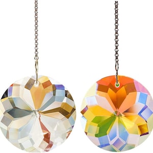 May include: Two round, faceted crystal suncatchers with iridescent rainbow colors. Each suncatcher is suspended by a silver-colored chain. The crystals have a geometric design, reflecting light in various directions.