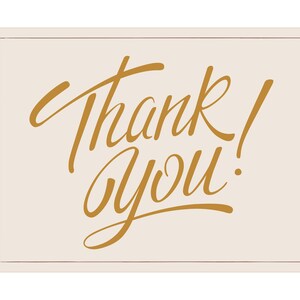 May include: A rectangular card with a cream background and a thin, light brown border. The words "Thank You!" are written in elegant, gold-colored script across the center of the card.
