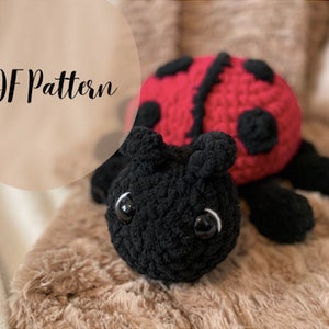 May include: A crocheted ladybug plush toy with black legs, red wings with black spots, and black eyes. The toy is lying on a brown fuzzy surface. PDF Pattern.