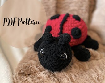 May include: A crocheted ladybug plush toy with black legs, red wings with black spots, and black eyes. The toy is lying on a brown fuzzy surface. PDF Pattern.