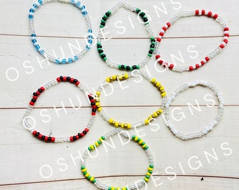 May include: Six beaded bracelets with different color combinations. The bracelets are made with clear beads and colored beads. The colors include red, white, blue, green, black, and yellow.