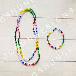 May include: A set of two beaded necklaces in red, green, yellow, blue, and black. The longer necklace is a waist bead, and the shorter necklace is a bracelet.