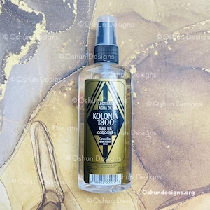 May include: A clear glass cologne bottle with a black and gold label. The label reads "KOLONIA 1800" and "EAU DE COLOGNE". The bottle has a black spray nozzle and contains a clear liquid. The bottle is 4 fl oz.