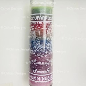 May include: A cylindrical candle with a clear glass exterior. The candle is multi-colored, transitioning from green to purple. Text and a hummingbird illustration are visible on the candle, with the words "CHUPARROS" and "HUMMINGBIRD" prominently displayed.
