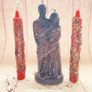 May include: Three black and red candles, two are tall and thin, one is a couple holding hands. The candles are covered in dried herbs and flowers. The text "OSHUNDESIGNS" is visible on the candles. The text "SHUN DESIGNS" is visible on a white card.