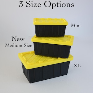 May include: Three rectangular storage containers with black bases and bright yellow lids, stacked in a pyramid arrangement. The text 3 Size Options, Mini, New Medium Size, and XL labels the containers. The base of the image shows Alex And Steve's Workshop.