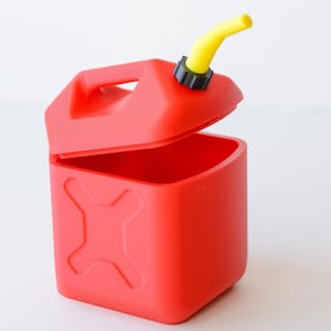 May include: A red, open-top container shaped like a gas can, featuring a yellow spout and a black cap. The container has a handle and an embossed X on the side. The design is a playful take on a fuel container.