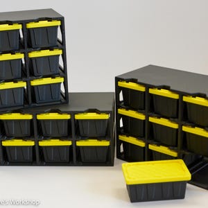 May include: A set of black storage racks with multiple compartments holding small black bins with bright yellow lids. One individual bin with a yellow lid sits in front of the racks. The text "Alex And Steve's Workshop" is visible at the bottom.