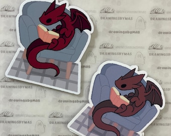 Puede incluir: Dos pegatinas de un dragón rojo y un dragón azul leyendo un libro mientras están sentados en una silla. Las pegatinas están sobre un fondo blanco con un patrón repetitivo de libros.