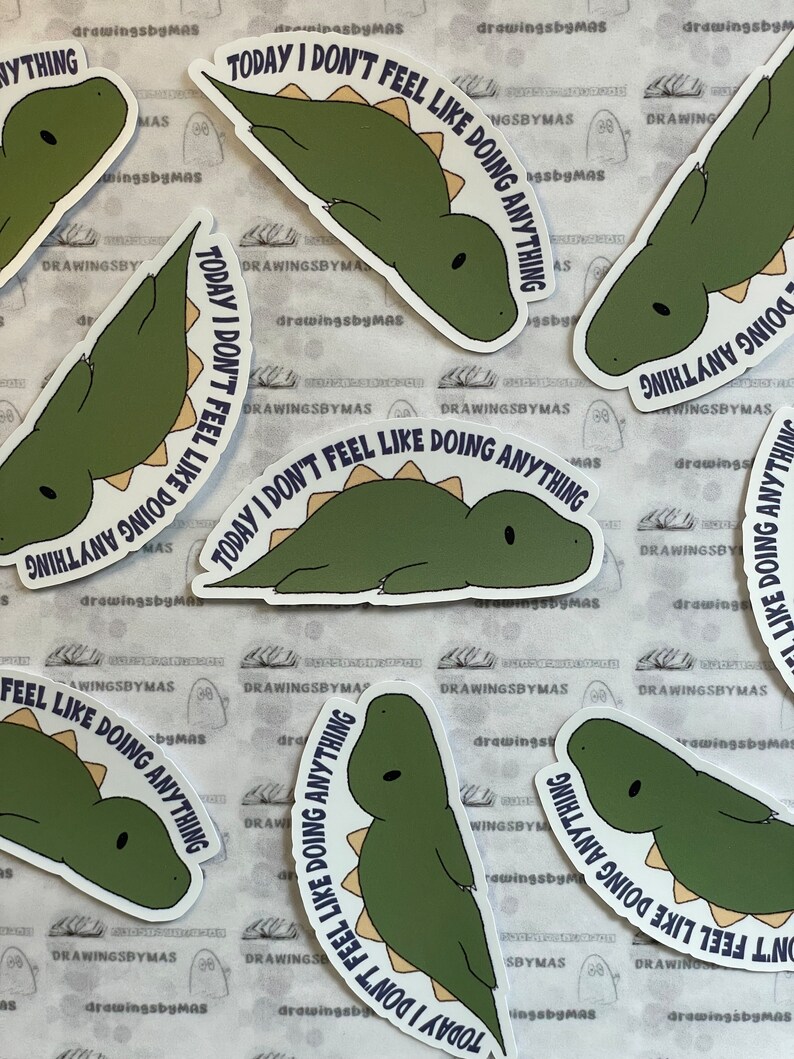 Puede incluir: Un conjunto de pegatinas con un dise&ntilde;o de dinosaurio de dibujos animados en tonos verdes y beige. El texto "TODAY I DON'T FEEL LIKE DOING ANYTHING" est&aacute; escrito en azul oscuro. Las pegatinas est&aacute;n sobre un fondo blanco.