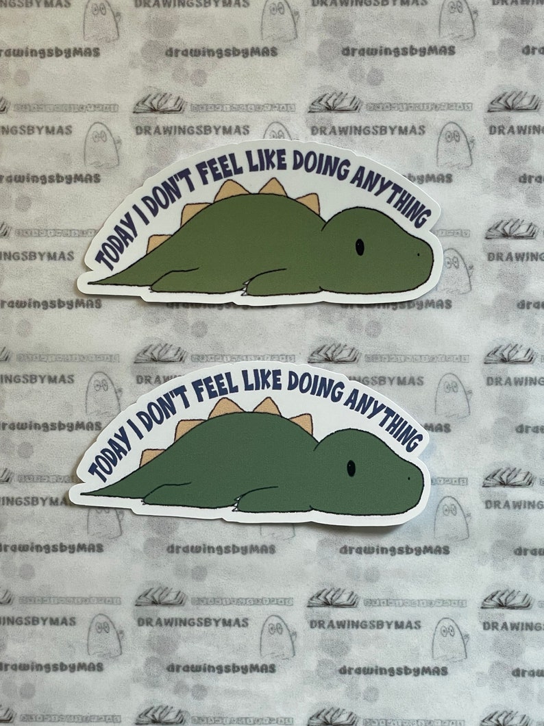 Puede incluir: Dos pegatinas con un dinosaurio verde con espina dorsal beige, tumbado. El texto azul marino "TODAY I DON'T FEEL LIKE DOING ANYTHING" est&aacute; arqueado sobre el dinosaurio. Las pegatinas est&aacute;n sobre un fondo estampado.