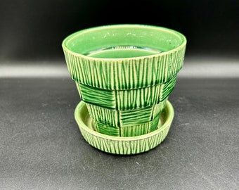 May include: A green ceramic planter with a matching saucer. The planter has a woven pattern and a slightly flared lip.