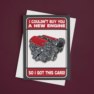 May include: Greeting card featuring a red and silver engine illustration. The card reads "I COULDN'T BUY YOU A NEW ENGINE" at the top and "SO I GOT THIS CARD!" at the bottom. The card is on a white envelope.