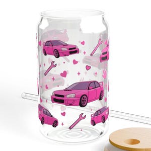 May include: A clear glass can-shaped drinking glass with a pink car and wrench pattern. The design includes pink cars, wrenches, hearts, and stars. The glass has a clear straw and a wooden lid.