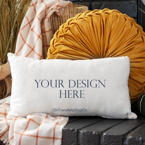May include: A white pillow with the text "YOUR DESIGN HERE" and "OnTrendMockupCo." on a black surface with a yellow velvet pillow, a plaid blanket, and a green pumpkin.