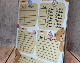 Op de afbeelding: Een Baby Daily Log notitieblok met secties voor voedingen, luiers, slaap, medicatie en spel. Het ontwerp bevat illustraties van bruine teddyberen, een babyfles, een luier en een medicijnflesje op een crème en witte achtergrond.