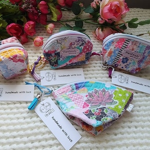 May include: Four small, colorful patchwork fabric coin purses with zipper closures and keychains. Each purse has a tag that reads "handmade with love".