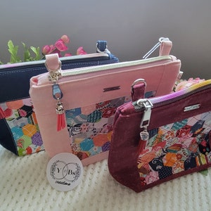May include: Three zippered pouches with colorful patchwork fabric designs. The pouches are navy blue, pink, and burgundy. Each pouch has a silver zipper and a tassel.
