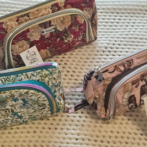 May include: Three zippered pouches with floral patterns. The pouches are made of fabric and have a zipper closure. The pouches are handmade with love.