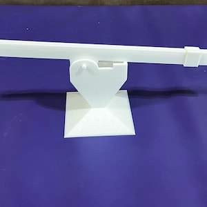 Puede incluir: Un juguete de balancín de plástico blanco con una base en forma de corazón. El balancín está equilibrado sobre un punto de pivote en el centro.