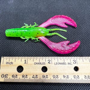 Peut inclure: Leurre de pêche en plastique souple en forme d'écrevisse de couleur verte et rose avec des points noirs. Le leurre mesure environ 5 cm de long.