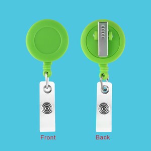 May include: A green retractable badge holder with a white card attached. The front of the holder is plain, while the back has a metal clip.
