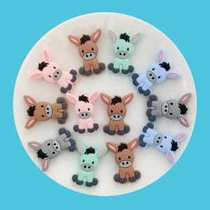 May include: A set of 10 silicone donkey charms in various colors, including brown, pink, blue, gray, and green. The charms are all in a sitting position with their ears up.