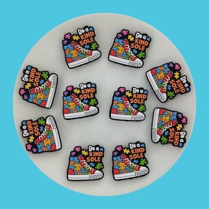 May include: Ten colorful shoe charms with a puzzle piece design and the text "Be a Kind Sole".