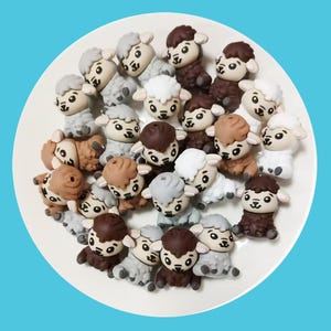 May include: A collection of 20 small, brown, grey, and white sheep figurines. The sheep are made of a soft, pliable material and have a cartoonish appearance.