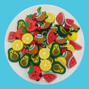 Peut inclure: Un ensemble de breloques en silicone colorées en forme de différents fruits, notamment des fraises, des citrons, des pastèques, des avocats et des noix de coco. Les breloques ont des visages mignons et sont parfaites pour ajouter une touche amusante aux bijoux, aux sacs ou aux porte-clés.