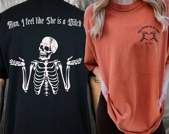 May include: Two black t-shirts with white graphic designs. One shirt features a skeleton with the text "Man, I feel like She is a Witch". The other shirt features two hands forming a heart with the text "Till Death Do Us Part Est. 2023".