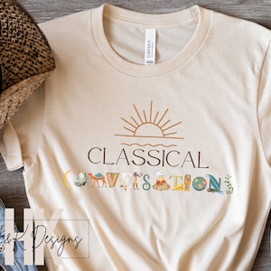 Pode incluir: Uma camiseta bege com um design gráfico de um sol se pondo sobre a água e o texto "CLASSICAL CONVERSATIONS". As letras da palavra "CONVERSATIONS" são substituídas por imagens de vários objetos, incluindo uma lua crescente, uma montanha, um camelo, um vulcão, um obelisco egípcio, um globo terrestre e uma onda.