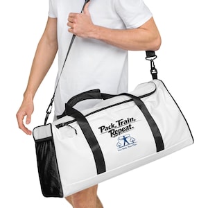 Könnte beinhalten: Weiße Sporttasche mit schwarzen Akzenten und einem schwarzen Schultergurt. Die Tasche trägt den Text "Pack, Train, Repeat." und eine Grafik einer Person beim Training. Eine schwarze Netztasche befindet sich an der Seite.
