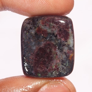 Könnte beinhalten: Ein rechteckiger, dunkelroter, grauer und weißer Edelstein mit einem marmorierten Muster.