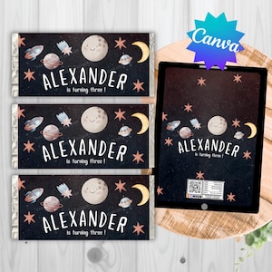 May include: Chocolate bar wrappers with a space theme. Each wrapper features a smiling moon, planets, rockets, and stars against a dark blue background. The name "ALEXANDER" and the phrase "is turning three!" are printed on the wrappers.