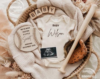 May include: A baby announcement featuring a baseball theme. A wooden sign says "We've been keeping a little secret, arriving December 2025." A white onesie with "Baby Wilson" is next to a baseball bat, glove, and ultrasound image, all in a woven basket.