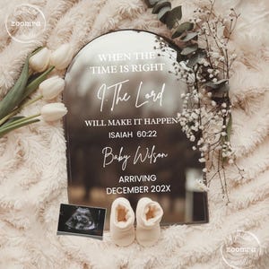 Puede incluir: Un letrero espejado con el texto "WHEN THE TIME IS RIGHT, 9. The Lord WILL MAKE IT HAPPEN, ISAIAH 60:22, Baby Wilson, ARRIVING DECEMBER 202X". El letrero está rodeado de flores blancas, patucos y una ecografía.
