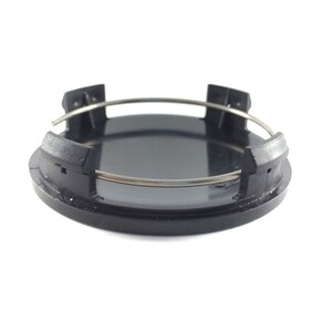 Puede incluir: Un centro de tapacubos de plástico negro con un anillo de retención de metal plateado. El centro del tapacubos tiene un diseño circular con cuatro pestañas para una fijación segura a una rueda. La imagen está tomada sobre un fondo blanco.