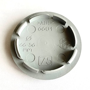 May include: Gray plastic wheel cover with the text "ABS 6601" and "66-56 mm" printed on it. The cover also has a recycling symbol and the number "75" printed on it.