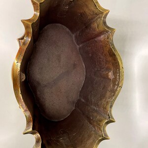 May include: A brass planter with a scalloped edge and a worn, aged finish. The planter is empty and ready for planting.