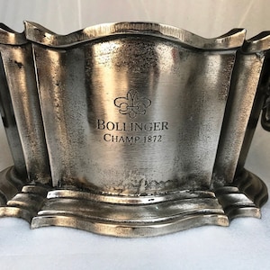 May include: Silver champagne bucket with two handles and a  Bollinger Champ 1872 inscription.