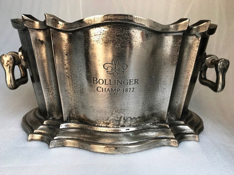 May include: Silver champagne bucket with two handles and a  Bollinger Champ 1872 inscription.