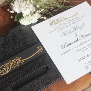 K&ouml;nnte beinhalten: Eine schwarze und goldene Hochzeitseinladung mit einem komplizierten floralen Design und arabischer Kalligraphie. Die Einladung lautet "Mr. and Mrs. Hani Medjid bitten um die Ehre Ihrer Anwesenheit bei der Hochzeit ihres Sohnes Adel Medjid & Rawand Arabeyyat, Tochter von Herrn und Frau Ahed Arabeyyat, Freitag, 28. April 2023 um 20:00 Uhr, Adel & Rawand, Ravello Banquets, 138 Eagle Rock Avenue, East Hanover NJ. 07936."