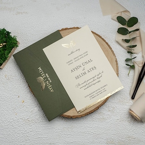 Juego de invitaciones de boda en dorado y negro con sobre verde oscuro.