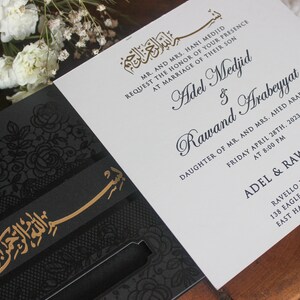K&ouml;nnte beinhalten: Eine schwarze und goldene Hochzeitseinladung mit einem komplizierten floralen Design. Die Einladung zeigt die Namen "Adel Medjid" und "Rawand Arabeyyat" sowie den Text "MR. AND MRS. HANI MEDJID REQUEST THE HONOR OF YOUR PRESENCE AT MARRIAGE OF THEIR SON" und "DAUGHTER OF MR. AND MRS. AHED ARABEYYAT". Die Einladung enth&auml;lt auch das Datum und die Uhrzeit der Hochzeit sowie den Ort.