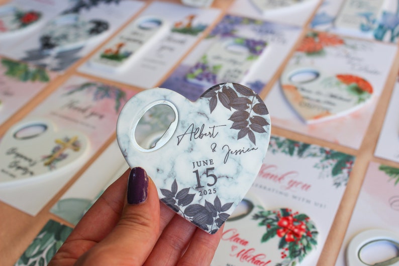 May include: White marble heart-shaped bottle opener with a black floral design and the text "Albert & Jessica" and "June 15, 2025".