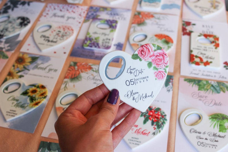 May include: A white heart-shaped bottle opener with a floral design and the text "Save the Date 05|OCTOBER|2025 Olivia & Michael".