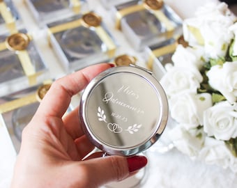 May include: A silver compact mirror with an engraved design that says "Miss Quinceañera 10.22.23".